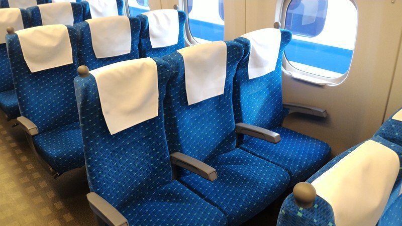 Blue upholstered seats arranged in rows inside an ordinary Shinkansen car
